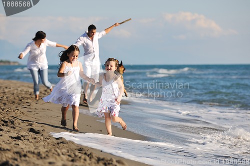 Image of happy family playing with dog on beach