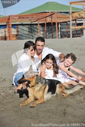 Image of happy family playing with dog on beach