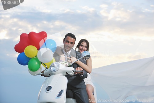 Image of just married couple on the beach ride white scooter