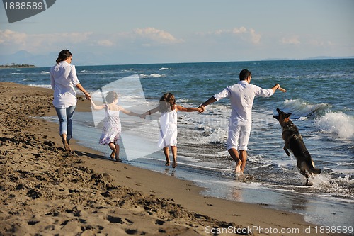Image of happy family playing with dog on beach
