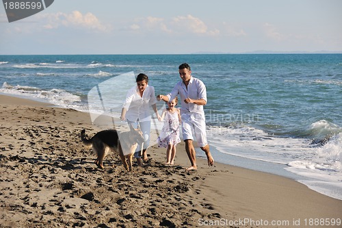 Image of happy family playing with dog on beach