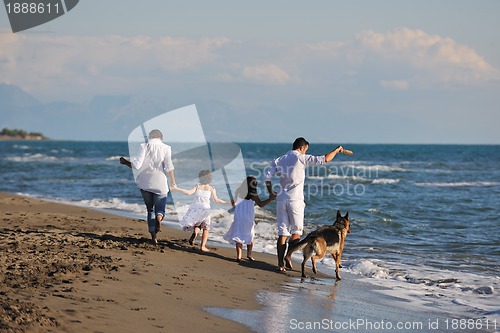 Image of happy family playing with dog on beach