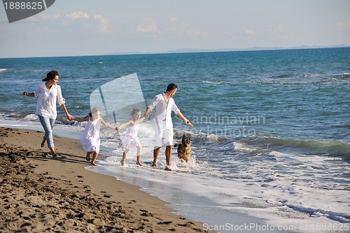 Image of happy family playing with dog on beach