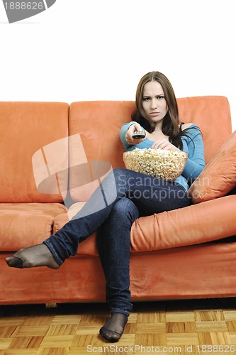 Image of young woman eat popcorn on orange sofa