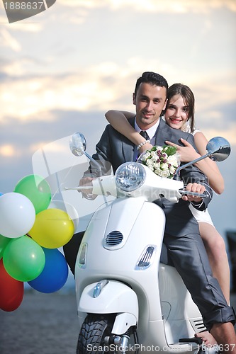Image of just married couple on the beach ride white scooter