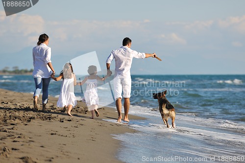 Image of happy family playing with dog on beach
