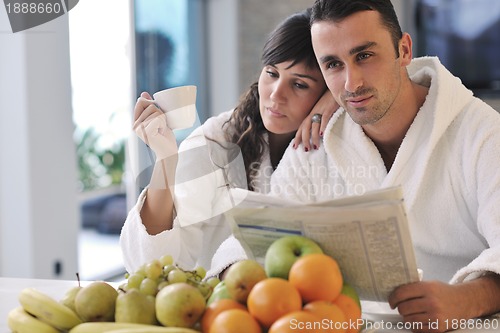 Image of Happy couple reading the newspaper in the kitchen at breakfast