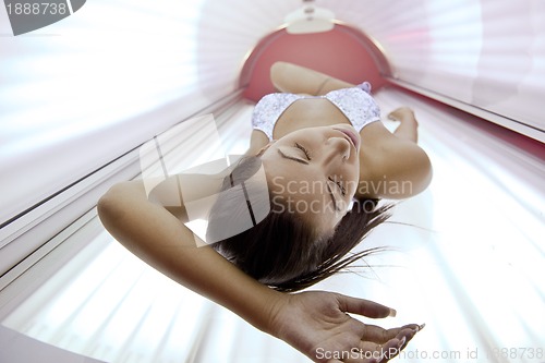 Image of Beautiful young woman tanning in solarium