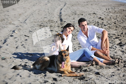 Image of happy family playing with dog on beach