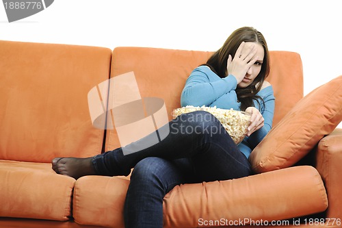 Image of young woman eat popcorn on orange sofa