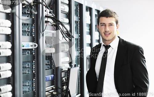 Image of businessman with laptop in network server room