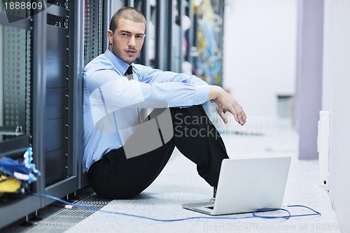 Image of businessman with laptop in network server room
