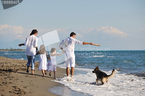 Image of happy family playing with dog on beach
