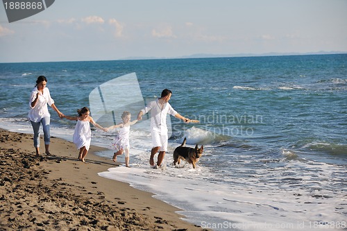 Image of happy family playing with dog on beach