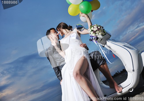 Image of just married couple on the beach ride white scooter