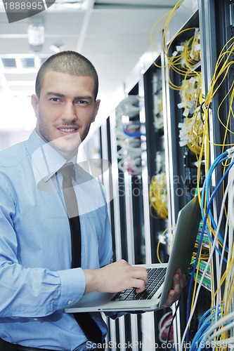 Image of businessman with laptop in network server room