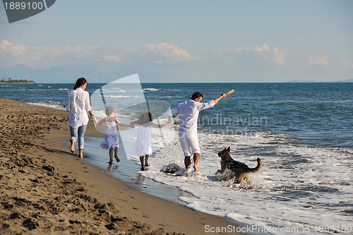 Image of happy family playing with dog on beach
