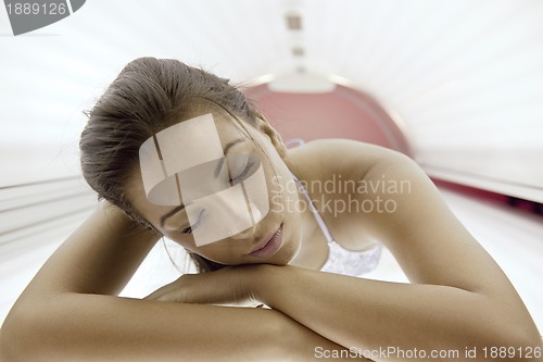 Image of Beautiful young woman tanning in solarium