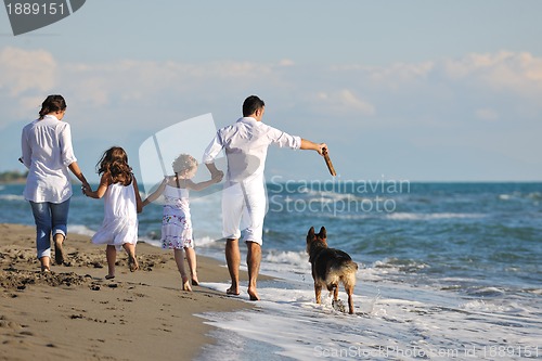 Image of happy family playing with dog on beach