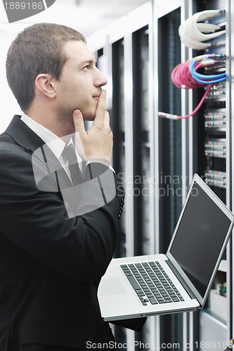 Image of businessman with laptop in network server room