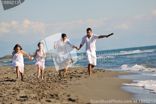 Image of happy family playing with dog on beach
