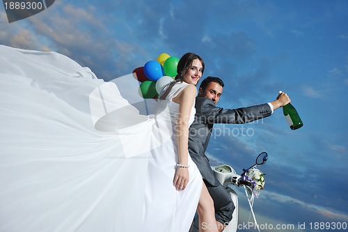 Image of just married couple on the beach ride white scooter