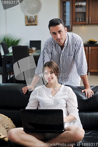 Image of joyful couple relax and work on laptop computer at modern home