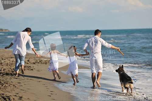 Image of happy family playing with dog on beach