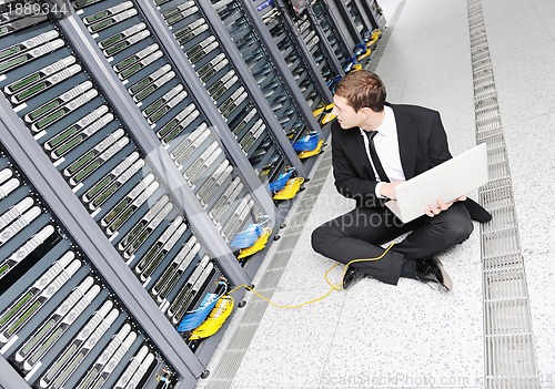 Image of businessman with laptop in network server room