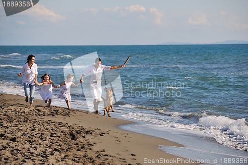 Image of happy family playing with dog on beach