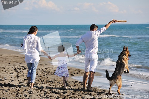 Image of happy family playing with dog on beach