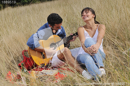 Image of happy couple enjoying countryside picnic in long grass