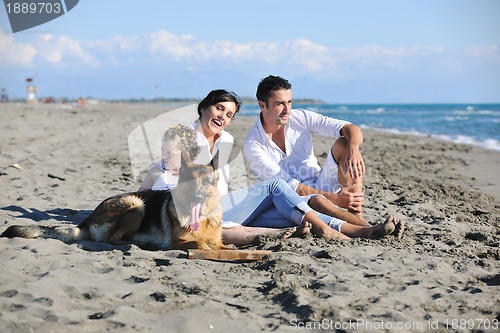 Image of happy family playing with dog on beach