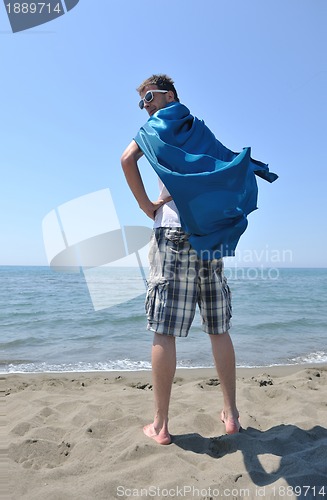 Image of funny superhero standing on beach
