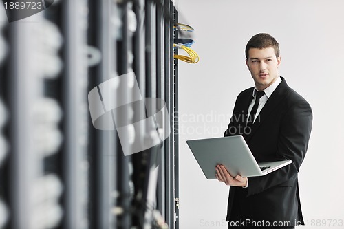 Image of businessman with laptop in network server room