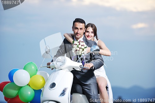 Image of just married couple on the beach ride white scooter