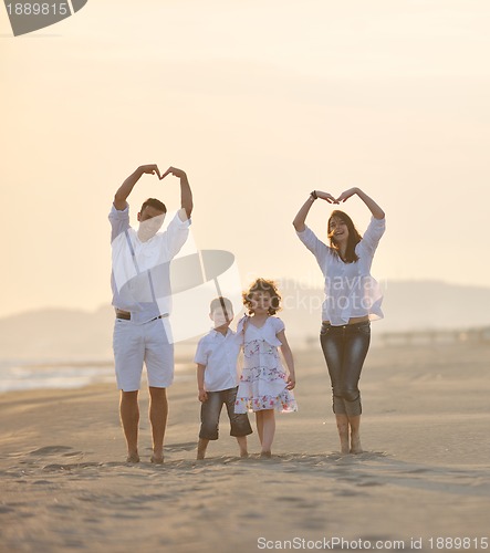 Image of happy young family have fun on beach at sunset