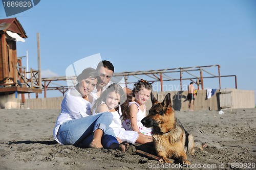 Image of happy family playing with dog on beach