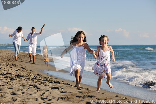 Image of happy family playing with dog on beach