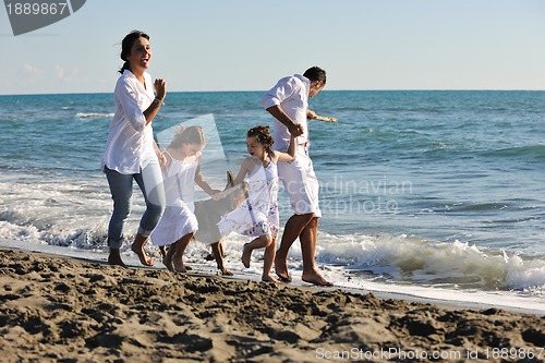 Image of happy family playing with dog on beach