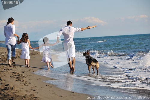 Image of happy family playing with dog on beach