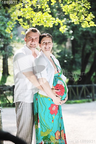 Image of Happy pregnant couple at beautiful sunny day in park