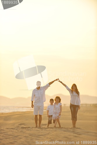 Image of happy young family have fun on beach at sunset