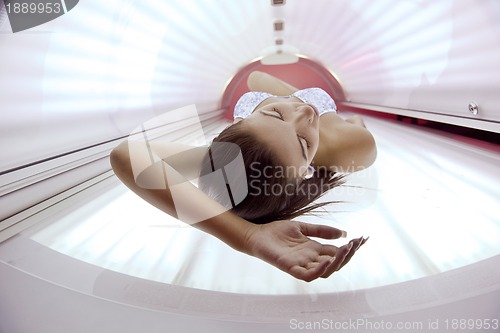 Image of Beautiful young woman tanning in solarium