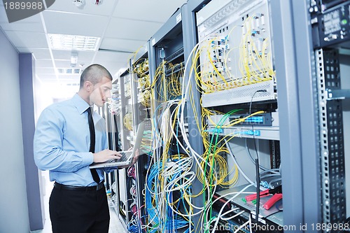 Image of businessman with laptop in network server room