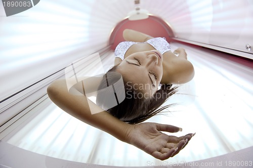 Image of Beautiful young woman tanning in solarium