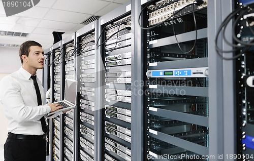 Image of businessman with laptop in network server room