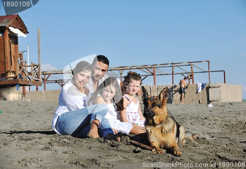 Image of happy family playing with dog on beach