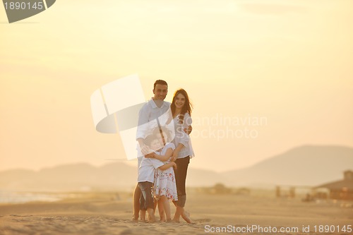 Image of happy young family have fun on beach at sunset