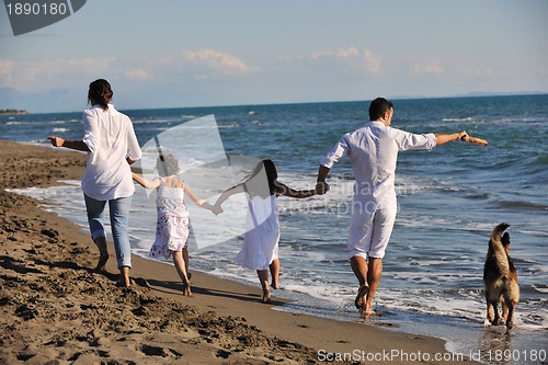 Image of happy family playing with dog on beach